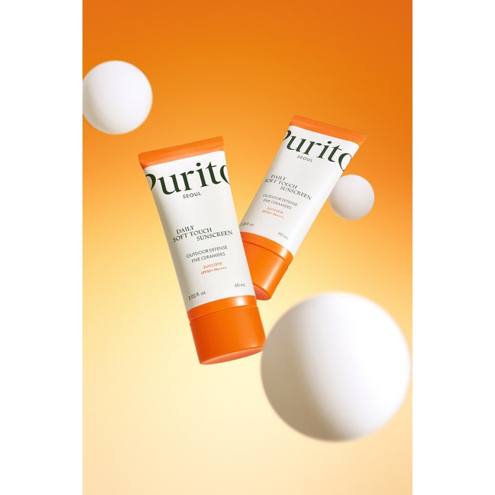 Purito Daily Soft Touch Sunscreen 60 ml daglig solkräm ansikte med ceramider i vita och orangea tuber bland vita bollar