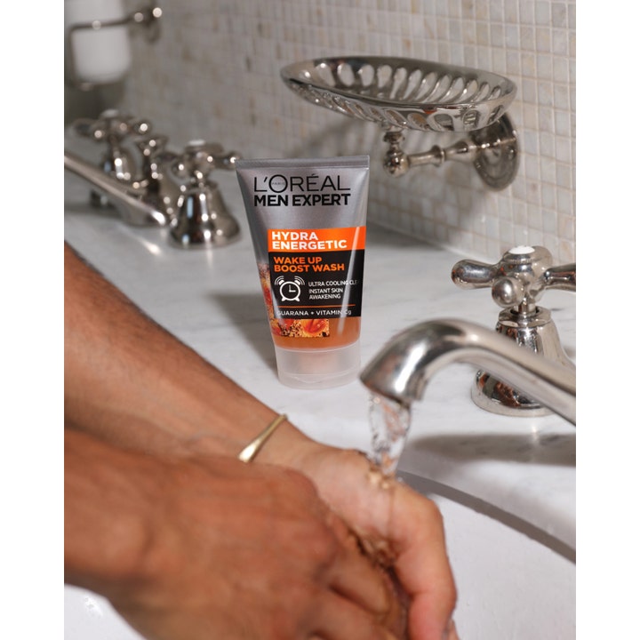 L'Oréal Paris Hydra Energetic Wash 100 ml energigivande ansiktsrengöring för män vid ett handfat med rinnande vatten.