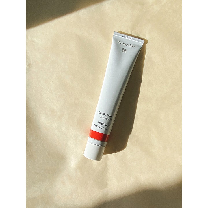 Dr. Hauschka Hand Cream 50 ml återfuktande handkräm i vit tub på beige texturerad bakgrund i naturligt ljus