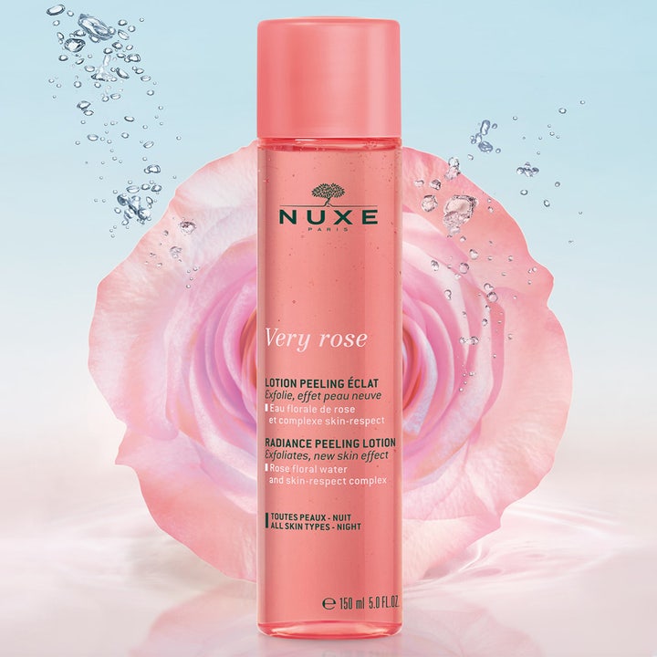 Nuxe Very Rose Peeling Lotion 150 ml kemisk peeling för strålande hy i en rosa flaska framför en stor ros