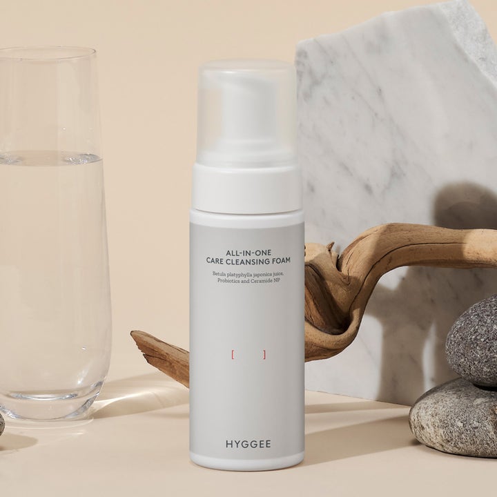 Hyggee All-In-One Care Cleansing Foam 150 ml rengöringsskum ger fukt i vit pumpflaska intill glas och stenar