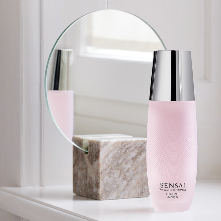 Sensai Cellular Performance Lotion II 125 ml ger återfuktande hudvård i rosa flaska framför en rund spegel.