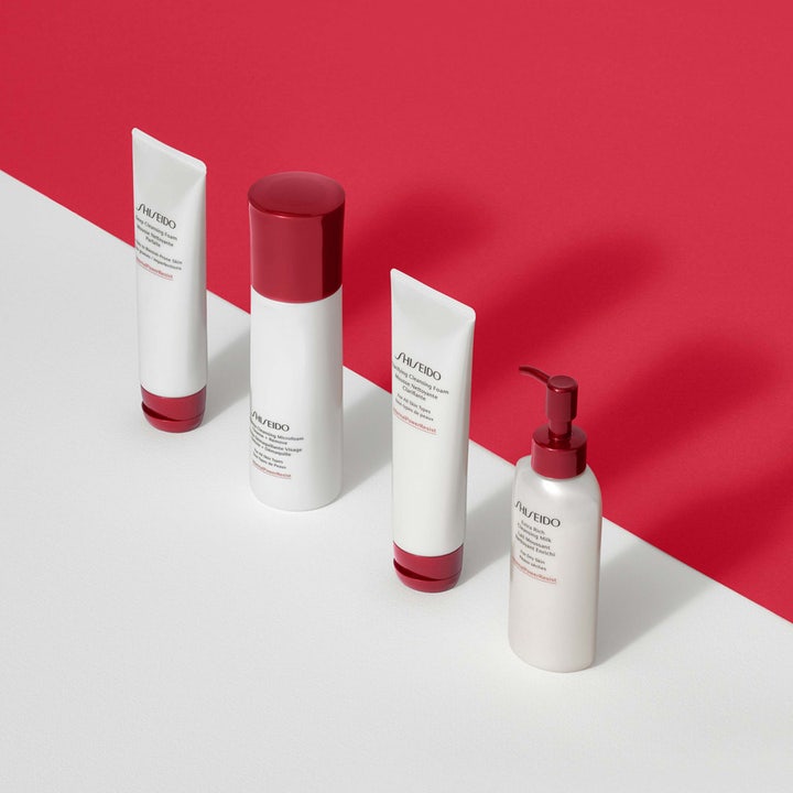 Shiseido Defend Preparation Cleansing Microfoam 180 ml rengöringsmousse ansikte i vit flaska med röd kork på röd bakgrund.
