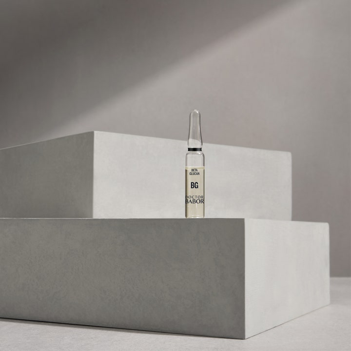 Babor DOC Instant Soothing Ampoule Serum Concentrate 14 ml lugnande beta glucan serum i glasampull på ett podium