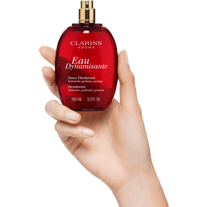 Clarins Eau Dynamisante Deodorant Spray 100 ml uppfriskande damdeodorant i röd glasflaska hållen i en hand