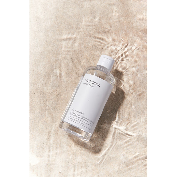 Mixsoon Bifida Toner 300 ml alkoholfri återfuktande toner i klar flaska på sand under krusande vatten.