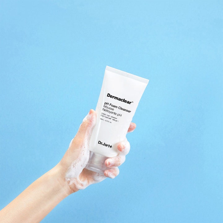 Dr.Jart+ Dermaclear pH Foam Cleanser 120 ml mild ansiktsrengöring i vit tub som hålls av en hand täckt i vitt skum