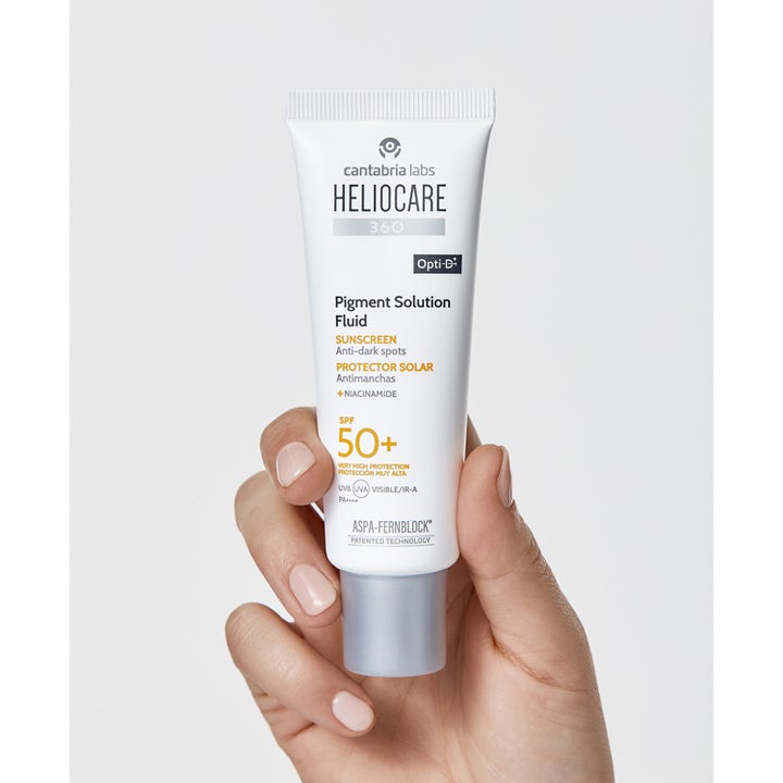 Heliocare Pigment Solution Fluid 50 ml niacinamide anti pigmentfläckar i vit tub med grått lock som hålls i en hand.