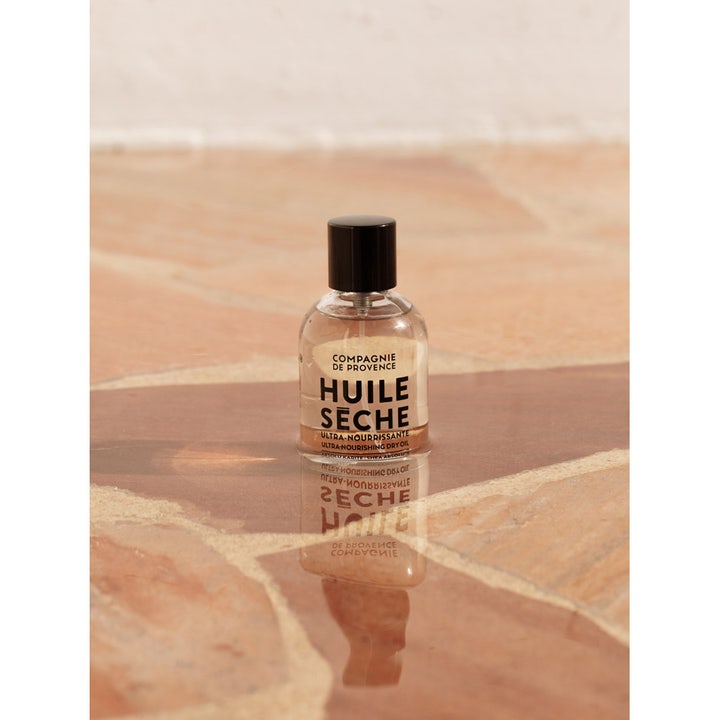 Compagnie de Provence Ultra Nourishing Dry Oil 100 ml i genomskinlig glasflaska på en varm stenyta
