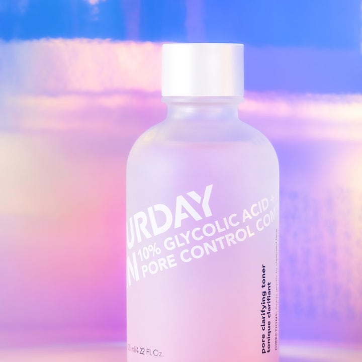 Saturday Skin Pore Clarifying Toner 125 ml toner med 10% glycolic acid i frostad flaska mot en drömsk bakgrund.
