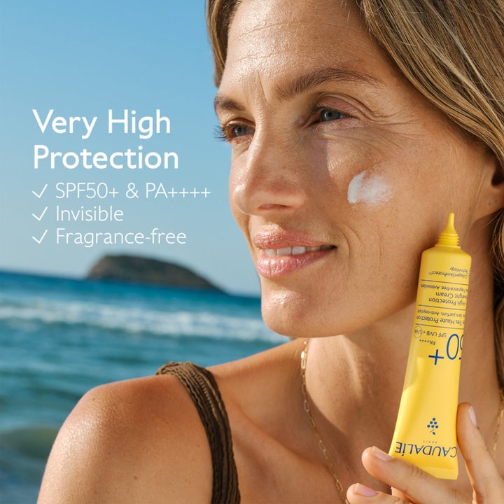 Caudalie Vinosun SPF50 40 ml solkräm för ansiktet på kvinna vid havet med lätt textur på kinden