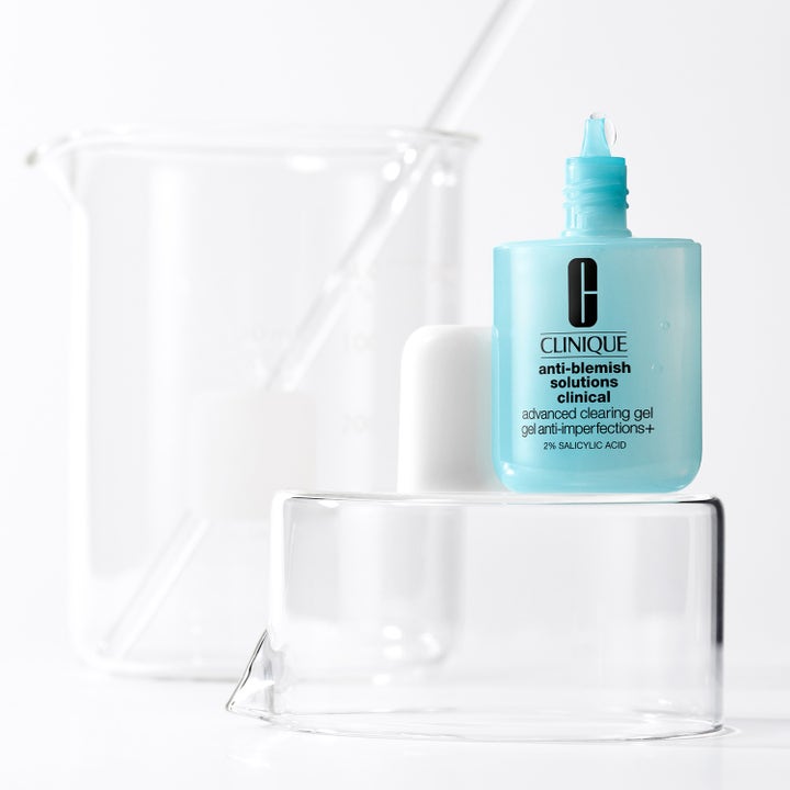 Clinique Anti Blemish Advanced Clearing Gel 20 ml med salicylsyra i ljusblå flaska bredvid laboratorieglas.
