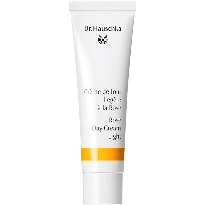 Dr. Hauschka Rose Day Cream Light lugnande roskräm dagkräm i en vit tub med en stilren orange rand och vitt lock.