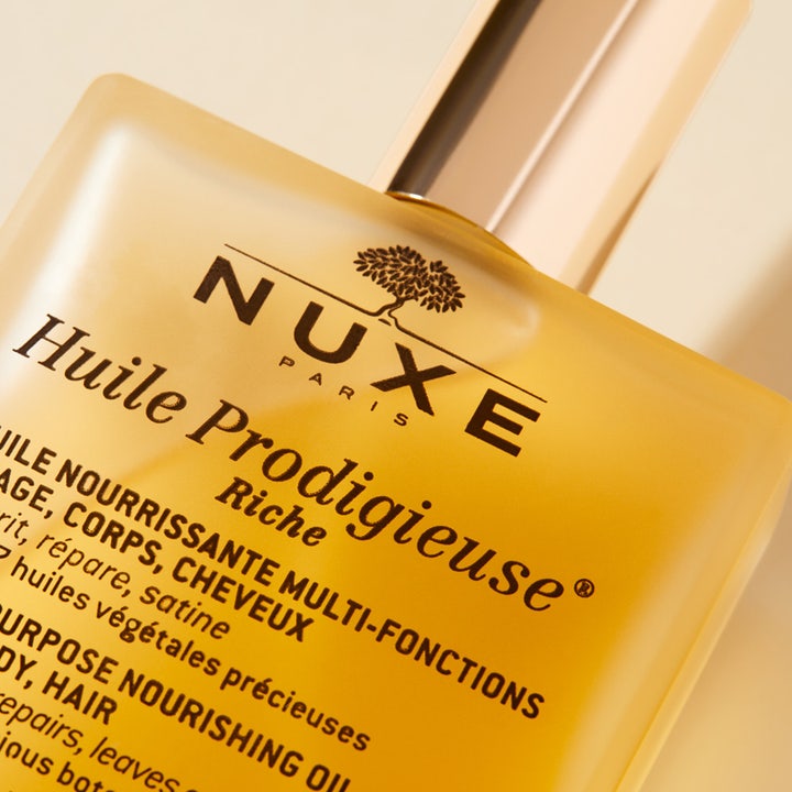 Nuxe Huile Prodigieuse Riche 100 ml fransk återfuktande kroppsolja i närbild på gyllene glasflaska med guldlock.