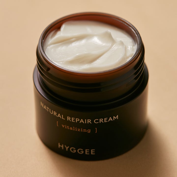 Hyggee Natural Repair Cream 50 ml återfuktande ansiktskräm för torr hy i mörk glasburk med krämig vit textur.