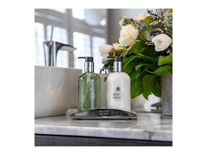 Molton Brown Refined White Mulberry 300 ml exklusiv handtvål pump och lotion på ett silverställ bredvid vita rosor