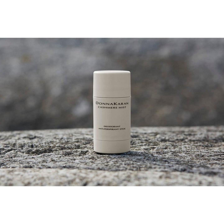 DKNY Cashmere Mist Deodorant Stick i beige hylsa som ger ett mjukt skydd placerad på en grå stenyta.