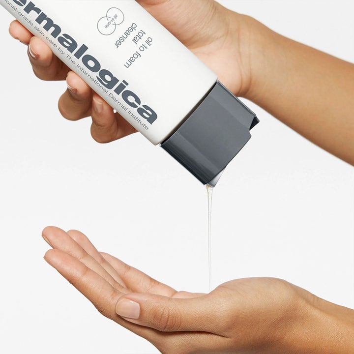 Dermalogica Oil to Foam Cleanser 250 ml ansiktsrengöring där genomskinlig olja hälls från vit flaska i en hand.