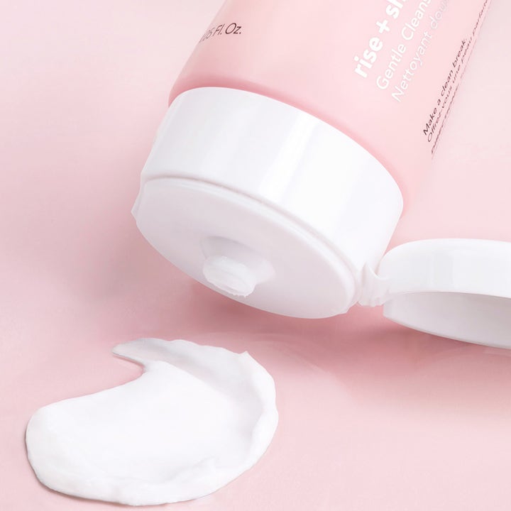 Saturday Skin Rise + Shine Gentle Cleanser 120 ml ansiktsrengöring i rosa tub med krämig vit formula på rosa yta.