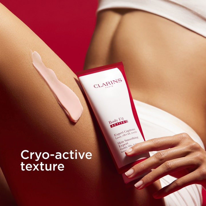 Clarins Body Fit Active 200 ml cellulitreducering med rosa aktiv formula på huden och röd tub för hudslätning.