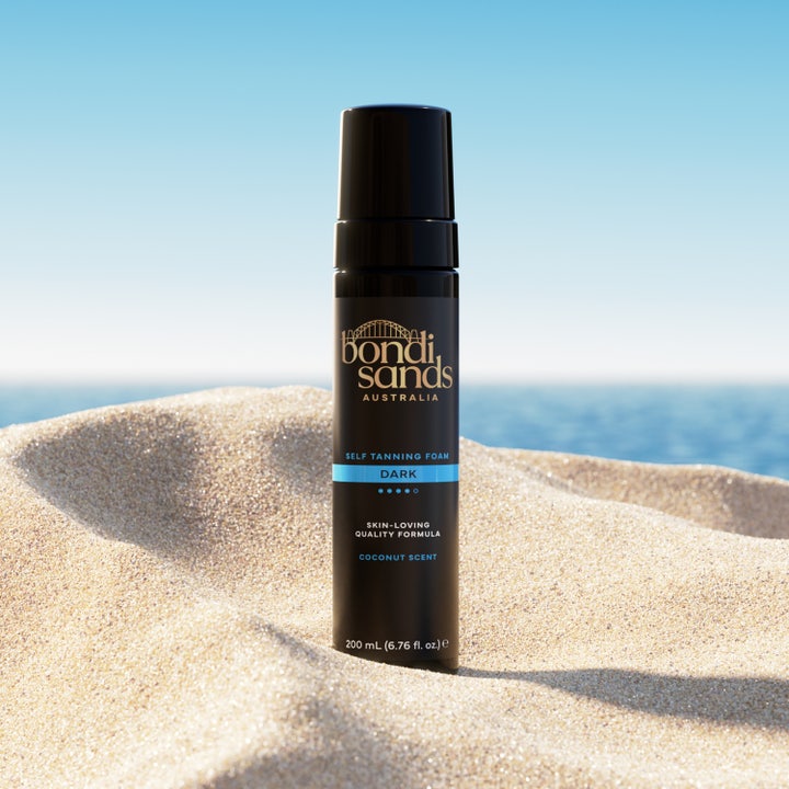 Bondi Sands Self Tanning Foam Dark 200 ml australienskt brun utan sol skum i svart flaska på en solig sandstrand.