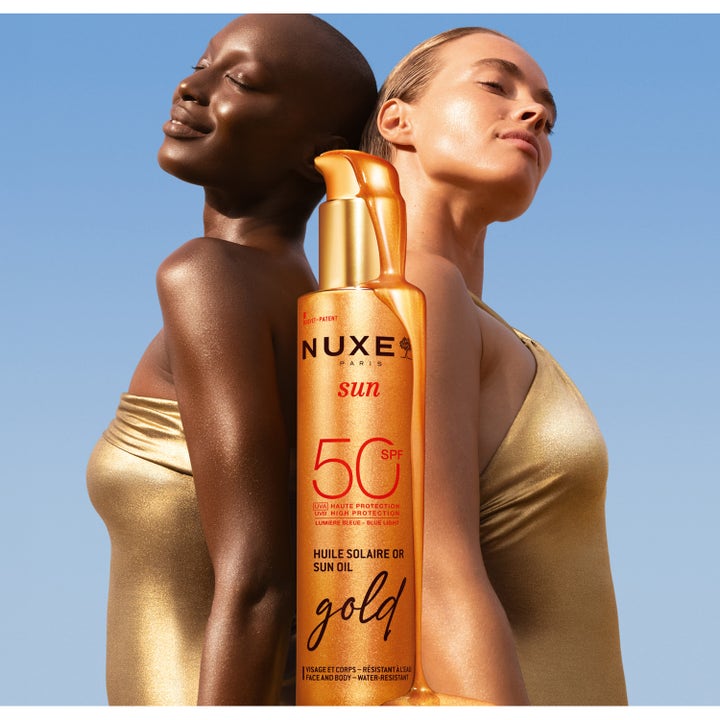 Nuxe Sun Tanning Oil Gold 150 ml lyxig sololja med spf50 ansikt och kropp på modeller i guld mot en blå himmel.
