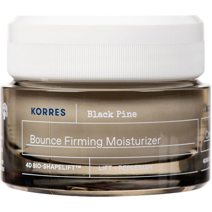Korres Black Pine Bounce Firming Moisturizer lyftkräm för ansiktet med svart tall i en mörk glasburk med vitt lock.