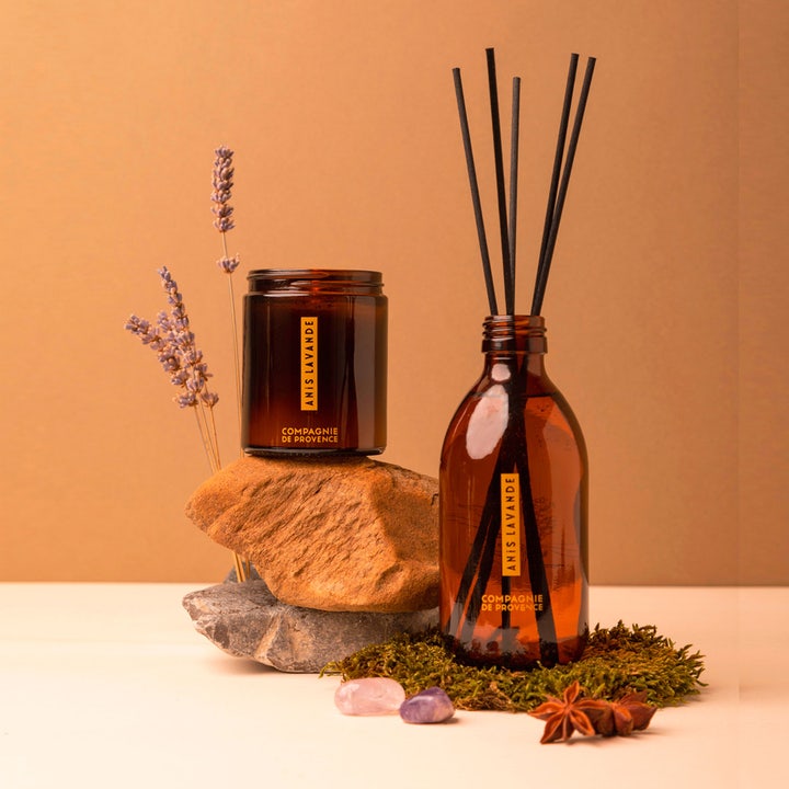 Compagnie de Provence Anise Lavender 495 ml flytande handtvål visas med matchande doftljus och rumsparfym i bruna glasflaskor.