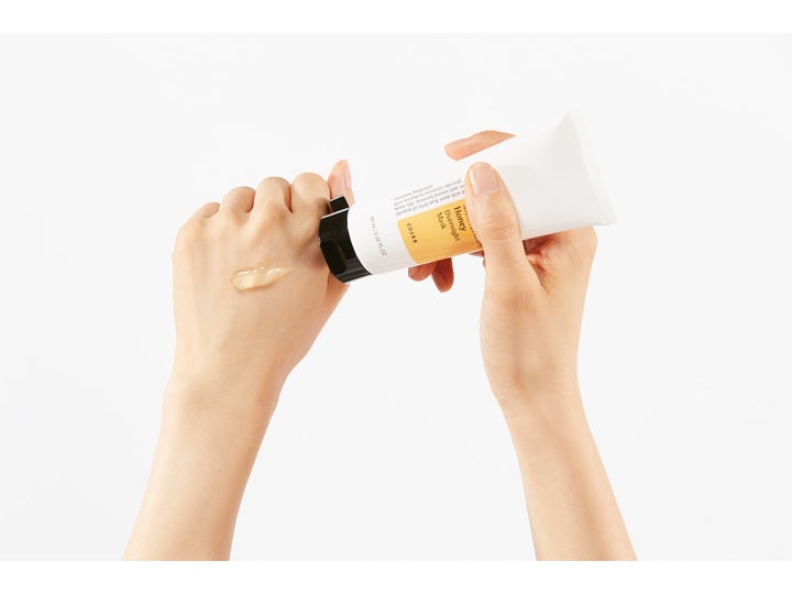 COSRX Ultimate Moisturizing Honey Overnight Mask 60 ml nattmask visar en honungsfärgad gel mot huden från en vit tub.