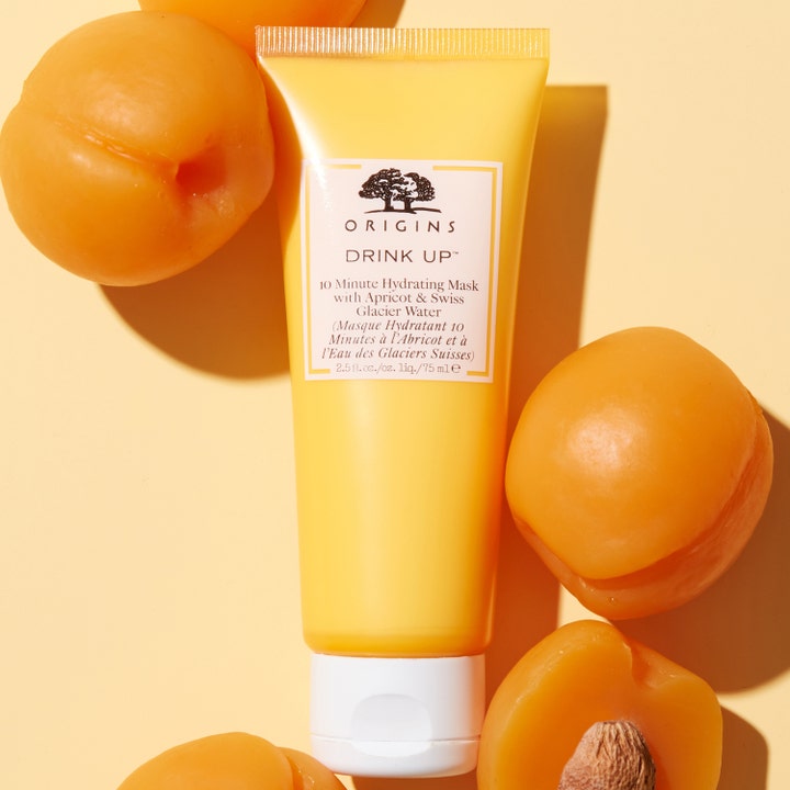 Origins Drink Up 10 Minute Mask 75 ml fuktgivande ansiktsmask i gul tub omgiven av färska aprikoser