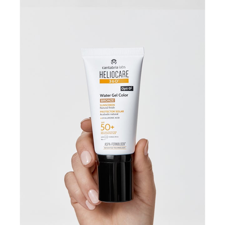 Heliocare Water Gel Color Bronze 50 ml brons solskydd med färg i en vit tub med svart lock som hålls i en hand