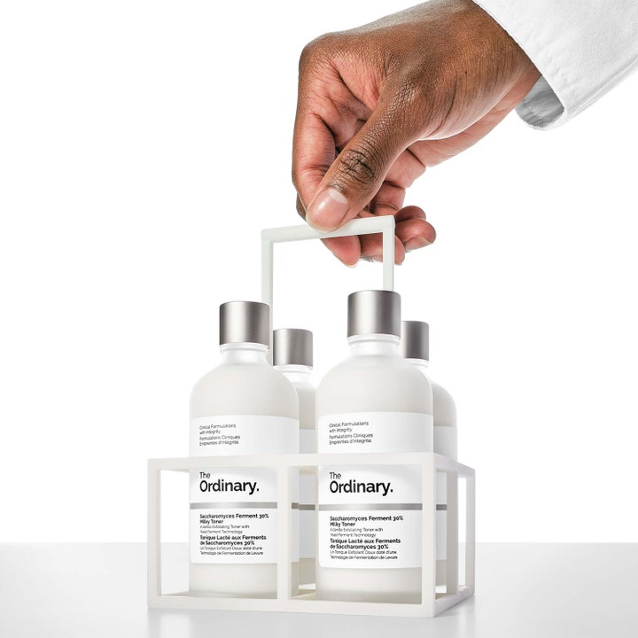 The Ordinary Saccharomyces Ferment 30% Milky Toner 100 ml återfuktande ansiktsvatten i vita flaskor som bärs av en hand.