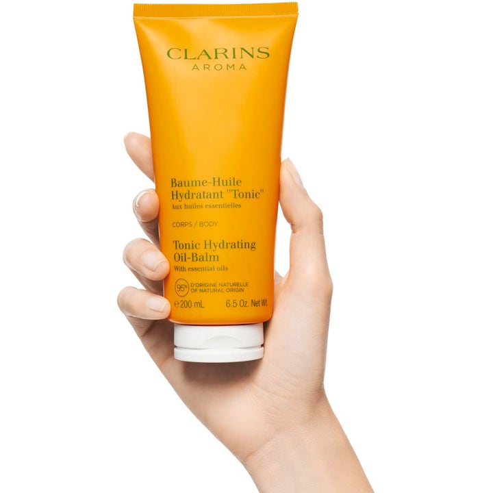 Clarins Hydrating Toning Body Balm 200 ml återfuktande kroppsvård i en orange tub som hålls i en hand