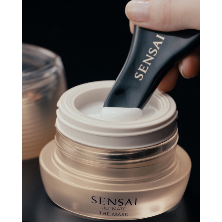 Sensai Ultimate The Mask 75 ml ansiktsmask mot rynkor med krämig vit formula i lyxig guldglasburk och svart spatel.