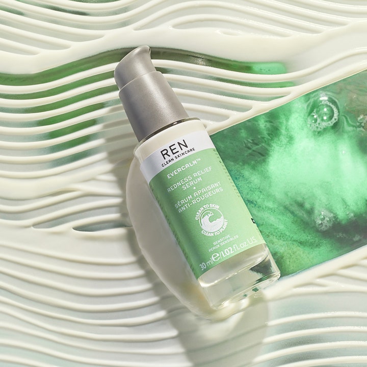 REN Evercalm Redness Relief Serum 30 ml lugnande ansiktsserum i pumpflaska på en vågig vit och grön textur.