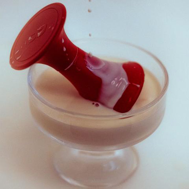 BornToStandOut Dirty Rice Eau de Parfum 15ml parfym röd flaska placerad i ett glas med en krämig beige vätska
