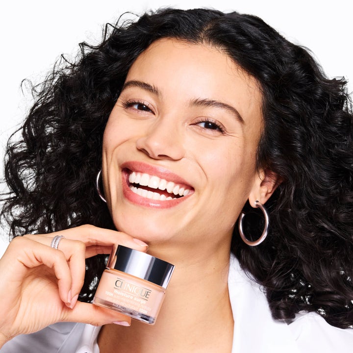 Clinique Moisture Surge Megastars återfuktande ansiktskräm i glasburk som ger lyster till en leende kvinna