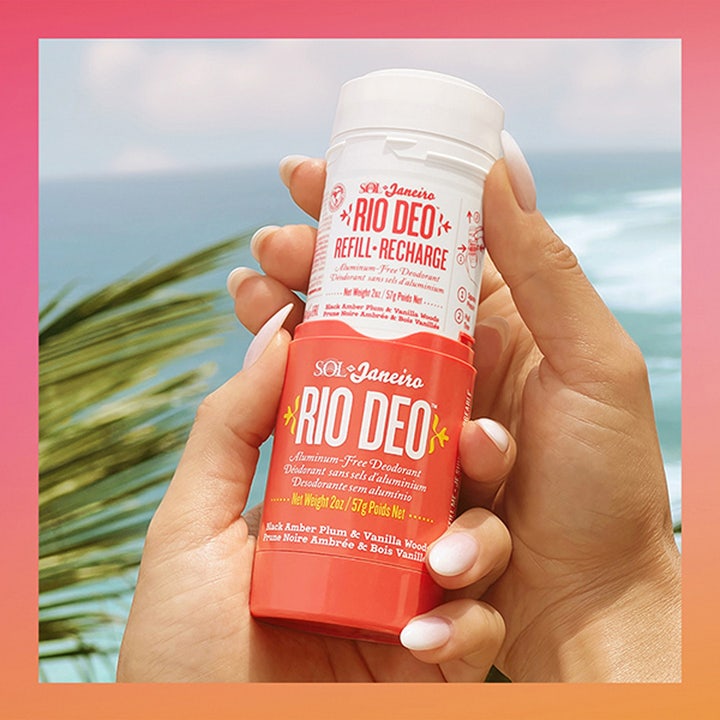 Sol de Janeiro Rio Deo 40 Deodorant Refill 57 ml aluminiumfri deodorant i röd hylsa hålls framför en solig strand.