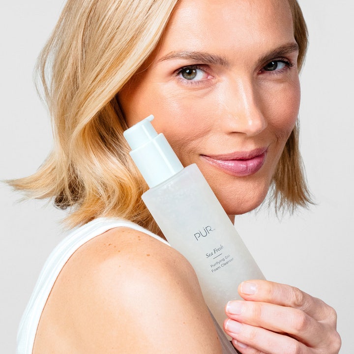 PÜR Sea Fresh Purifying Gel Foam Cleanser 150 ml ansiktsrengöring PÜR i frostad flaska som hålls av en kvinna