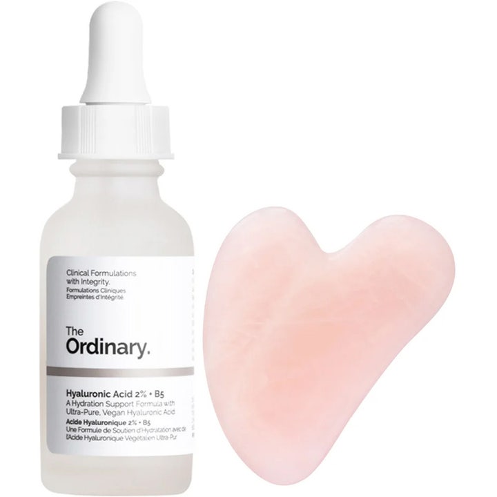 The Ordinary Hyaluronic Acid 2% + B5 återfuktande serum i frostad flaska bredvid en hjärtformad rosa gua sha.