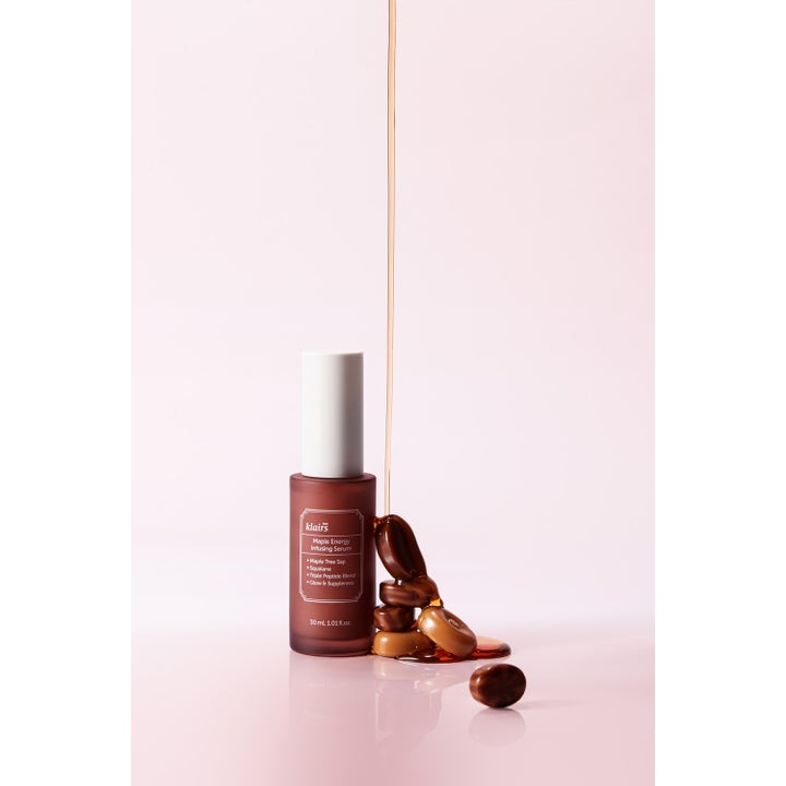 Klairs Maple Energy Infusing Serum 30 ml ger glow i en brun glasflaska bredvid rinnande gyllene lönnsav.