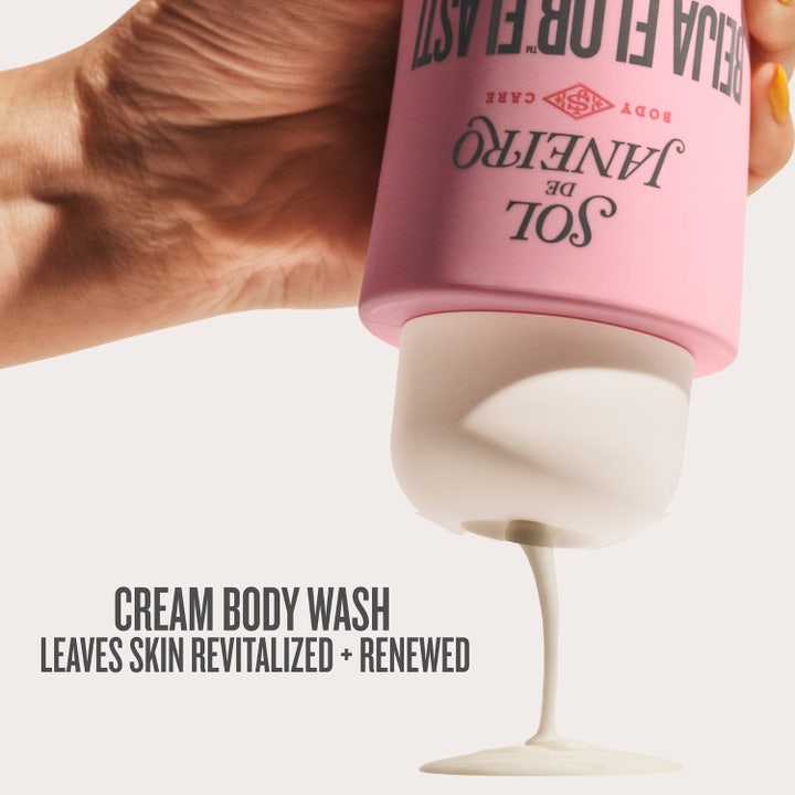 Sol de Janeiro Beija Flor Renewing Body Wash 385 ml i rosa flaska omgiven av löddrande skum och exfolierande blomdryror.