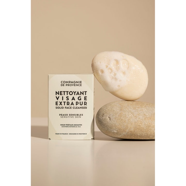 Compagnie de Provence Solid Face Cleanser 85 g ansiktsrengöring känslig hy visar fast tvål med vitt lödder på runda stenar.