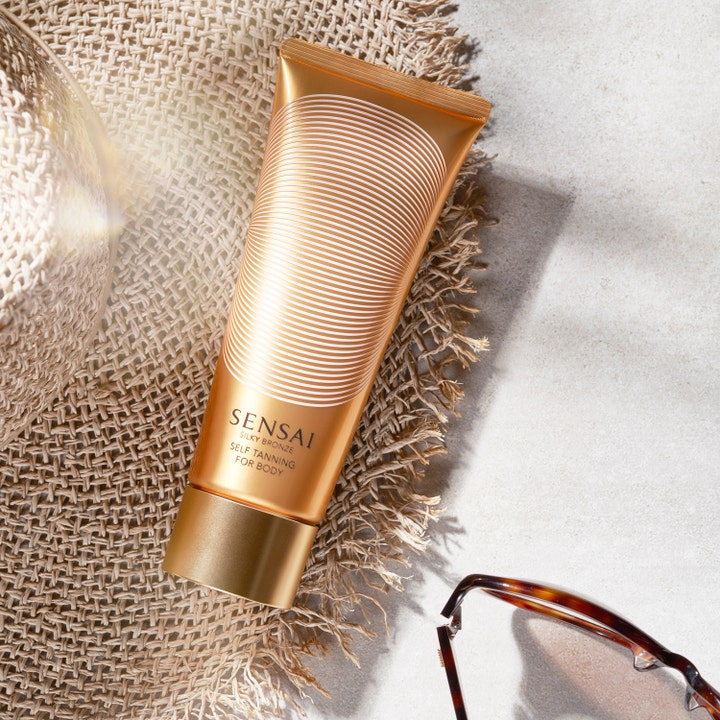 Sensai Silky Bronze Self Tanning For Body 150 ml fuktgivande brun utan sol kropp i guldglänsande tub på en solhatt