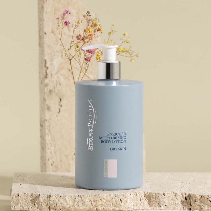 Beauté Pacifique fuktgivande kräm 500 ml bodylotion för torr hud i ljusblå pumpflaska bredvid torkade blommor.