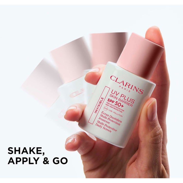 Clarins UV Plus 30 ml solkräm för ansiktet SPF 50+ i vit flaska med rosa lock som skakas i en hand.