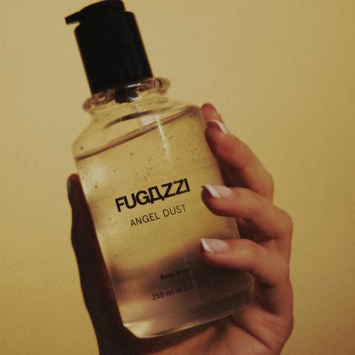Fugazzi Angel Dust 250 ml mjukgörande duschtvål i en genomskinlig flaska med svart pump som hålls i en hand