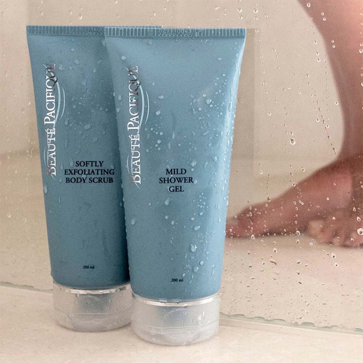 Beauté Pacifique Softly Exfoliating Body Scrub 200 ml ger mjuk hud i blå tub täckt av vattendroppar i duschen