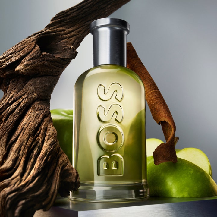 Hugo Boss Boss Bottled deostick herr 75 ml i glasflaska omgiven av friska gröna äpplen, kanel och trä
