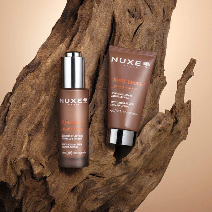 Nuxe Men Anti Age Cream 50 ml föryngrande ansiktskräm och serum i bruna förpackningar på en trädstam